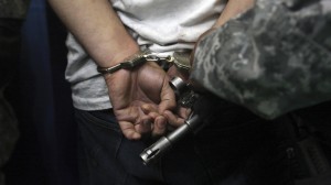 Cesar Cervantes, a suspected leader of the drug gang "The Resistance," gets his handcuffs adjusted during a presentation to the media in Guadalajara