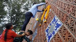 People place flowers on a wave-shaped tsunami monument for victims of the 2004 tsunami in Ban Nam Khem